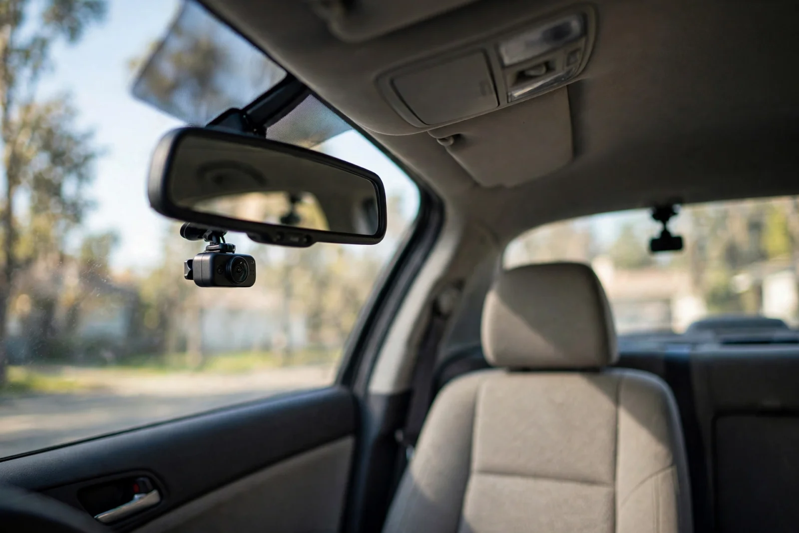 Front and rear dash cam behind rearview mirror, second camera on rear windshield, daylight.